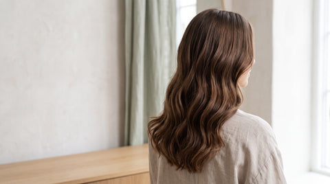 Healthy mid-brown wavy hair in soft daylight, seen from behind
